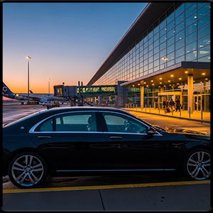 Luxury black sedan parked in front of an airport terminal, early morning, realistic lighting Luxury black sedan parked in front of an airport terminal, early morning, realistic lighting