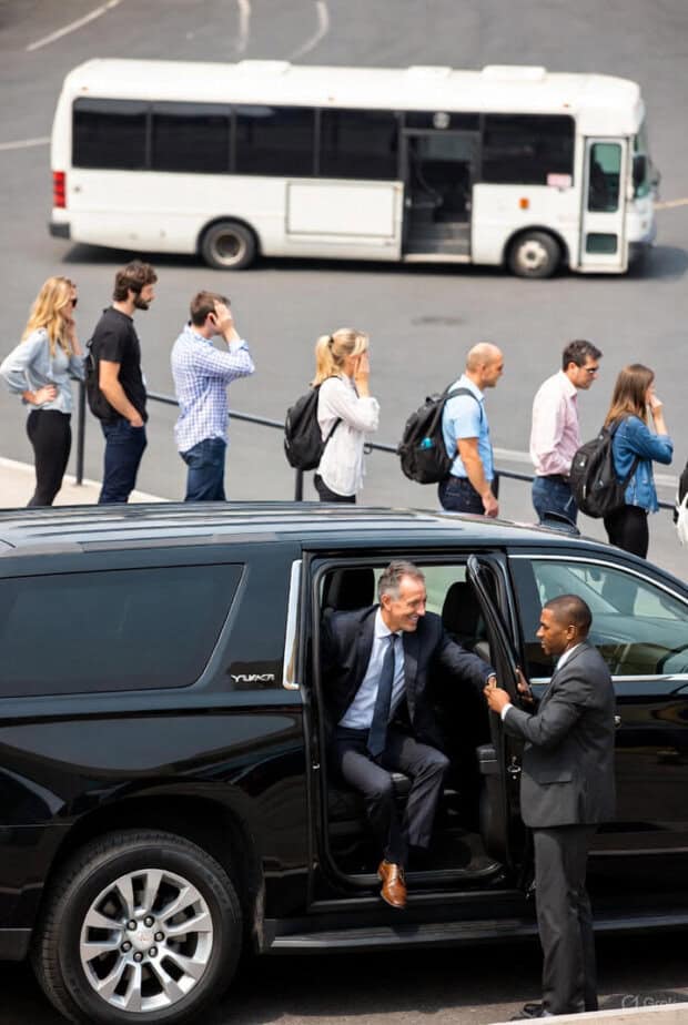 Group lining up for shuttle bus and a business man getting out of a black car