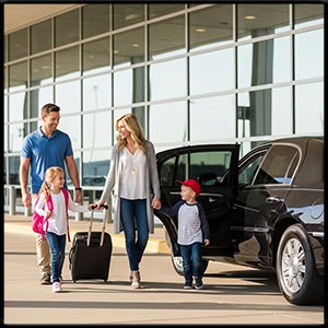 Happy family walking to a modern black town car at the MSP airport